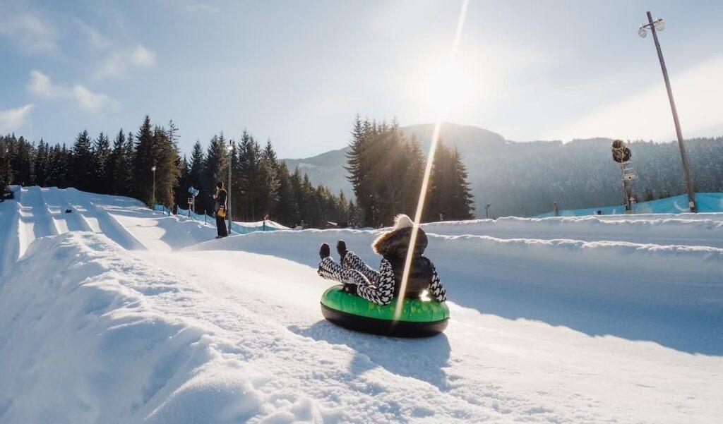Tubing at Whistler tube park in winter surrounded by snow on a sunny day