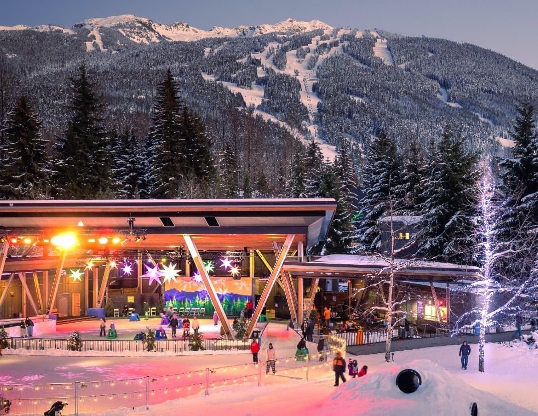People ice skating at Whistler's Olympic Plaza in winter surrounded by snow